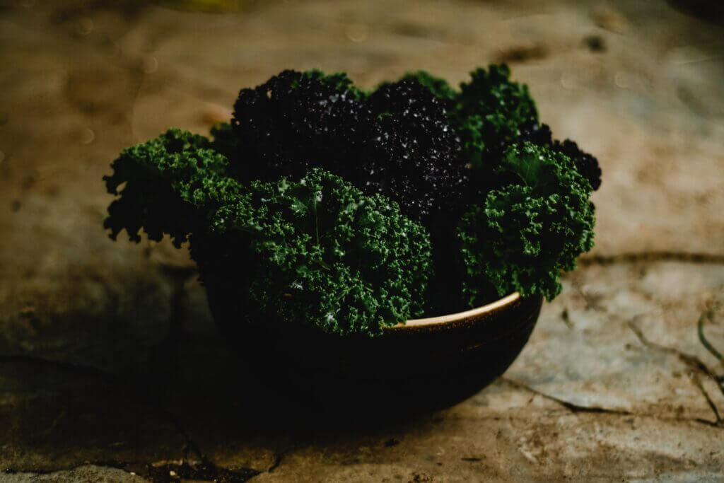 A bowl of Kale on a rustic wooden surface.